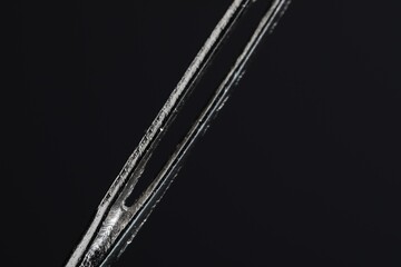 Sewing needle on black background, macro view