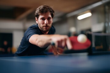 A determined man intensely playing table tennis, skillfully reaching for the ball with a paddle, indoors.