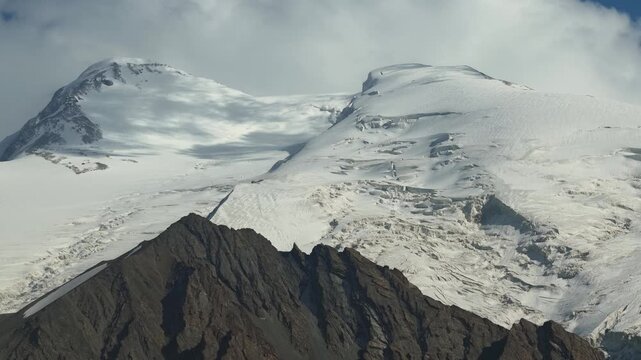 Aerial view of snow-capped mountains and rocky peaks in the Baisha Lake area, with a contrast of bright white snow and dark mountain rocks, Baisha Lake, China.