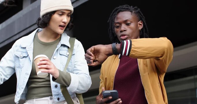 Diverse friends greeting on outdoor steps tapping smartwatch to check time viewing phone directions