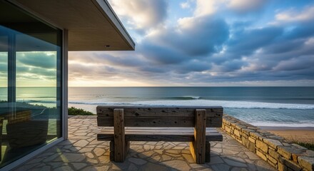 Scenic Ocean View from Coastal Home with Wooden Bench and Cloudy Sky at Sunset
