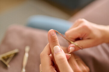 Closeup of trimming fingernail with nail scissors indoors