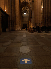 Directional arrow inside Salamanca cathedral, Spain. Interior of Salamanca cathedral with arrow on stone floor, gothic columns and warm light in UNESCO heritage city