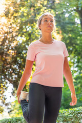 vertical Blonde girl runner stretching leg outdoors in park