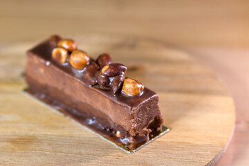 Delicious chocolate dessert bar topped with glossy hazelnut on a wooden board, perfect for sweet indulgence and gourmet presentation.