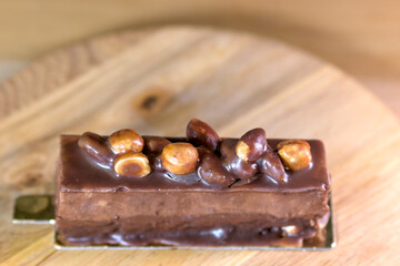 Delicious chocolate dessert bar topped with glossy hazelnut on a wooden board, perfect for sweet indulgence and gourmet presentation.