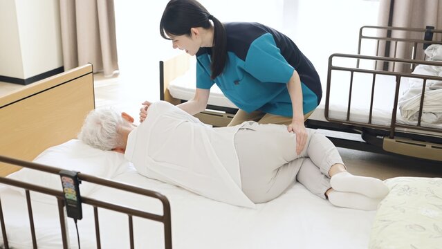 高齢者の体位変換を行うアジア人介護士