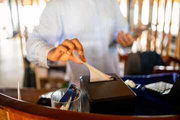 Modern hospitality, a smiling waiter accepts contactless payment from a happy customer,