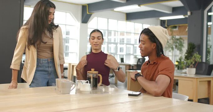 Diverse coworkers welcoming arriving Indian colleague engaging coffee chat in break area at table