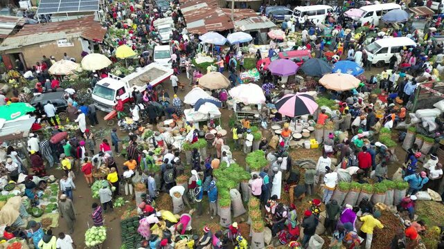 Jos, Nigeria - 25 September 2025: Aerial view of a vibrant market scene filled with colorful umbrellas and bustling crowds buying and selling fresh produce.