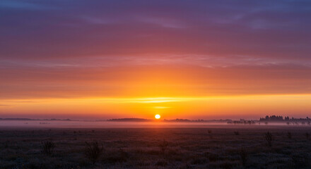 Sunrise over misty landscape with vibrant orange and purple sky  
