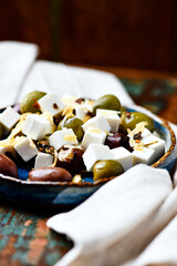 Green and kalamata olives and feta cheese on rustic wooden background. Soft focus.	