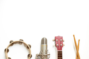 Musical instruments for band - small guitar, drumsticks and tambourine with studio microphone. Recording music in a studio