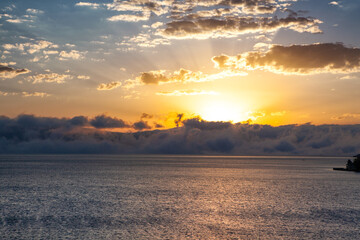 Sunset over the sea with clouds and rays of light on the horizon