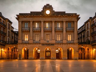 Constitución Plaza in San Sebastian, Spain, with its neoclassical arches, balconies, and clock...