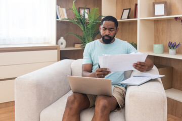 Young university student, freelancer business man, working at home on laptop computer, testing new innovative technology and online internet tools while sitting in home office.