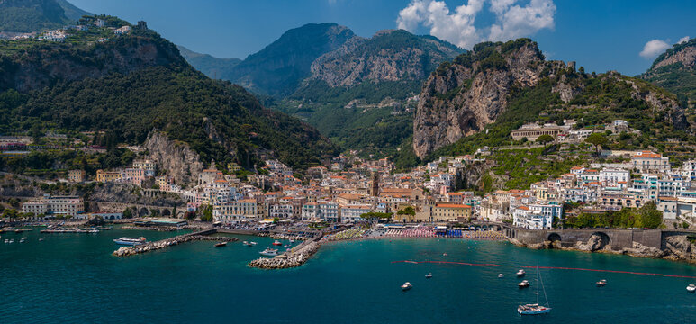 Aerial view of Almalfi, a coastal city nestled between towering mountains and the azure sea, with boats dotting the water, Amalfi Coast, Campania, Italy.