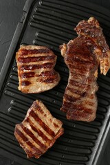 Delicious grilled beef meat on black table, top view