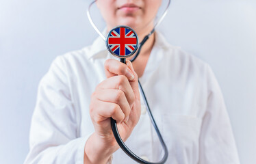 Female doctor holding stethoscope with United Kingdom flag. National health system of United Kingdom