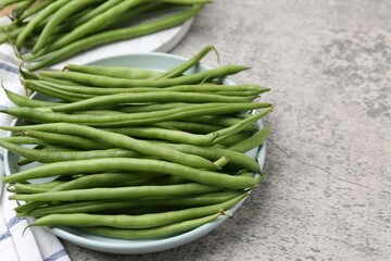 Fresh green bean pods on grey textured table, closeup. Space for text