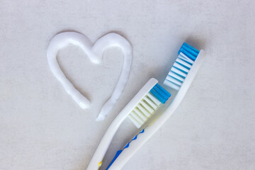 Flat lay composition with heart shape made of toothpaste and  toothbrush  on white background. The concept is dental and oral care products.