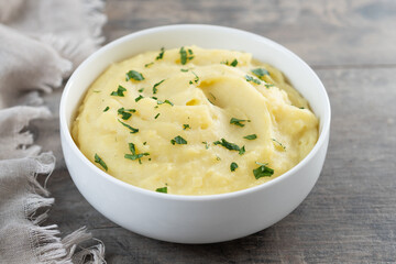 Mashed potatoes in white bowl on wooden table