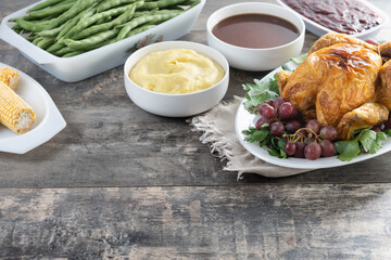 Thanksgiving roasted turkey with mashed potatoes, cranberry sauce and green beans on rustic wooden table. Copy space