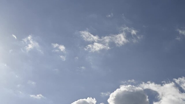 White and gray autumn clouds cross the sky from top left to bottom right. Blue sky, sunny afternoon with cumulus clouds passing quickly. Low-angle timelapse looping seamless.