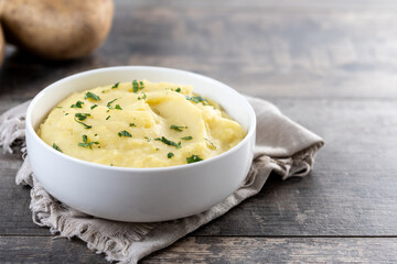 Mashed potatoes in white bowl on wooden table. Copy space