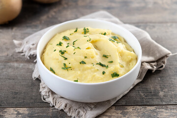 Mashed potatoes in white bowl on wooden table