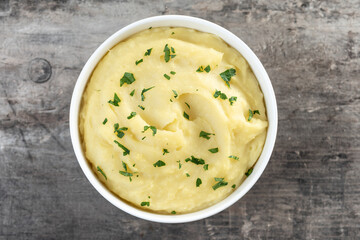 Mashed potatoes in white bowl on wooden table. Top view