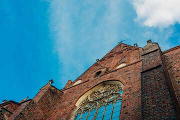 intricate facade of a Gothic church is set against a bright blue sky, wroclaw, Poland