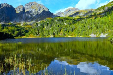 Fototapeta premium View of Unterere Zwiefler lake with a reflection in the water bellow the mountain peaks in Sölktäler nature park in Niedere Tauern, Styria, Austria