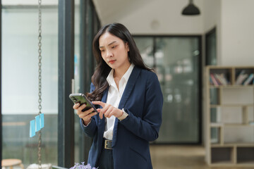 Businesswoman using smartphone in modern office, reading news and checking messages