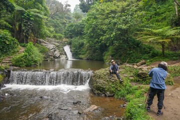 Obraz premium Photographer Picturing Adventurous Travelers In Serene Beauty Of Waterfall