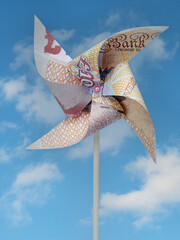 British Pound banknote cut into toy windmill shot on blue background