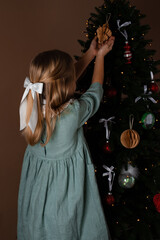 Cute girl is decorating the Christmas tree indoors. Merry Christmas and Happy New Years. Vertical orientation.
