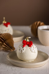 Christmas ball cakes with red bows and snowflakes, cup of coffee and paper toys on a table. Vertical orientation.