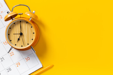 Alarm clock is on calendar with pencil, top view. Planning and time management concept