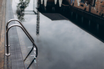 Grab bars reflecting in empty swimming pool on rooftop