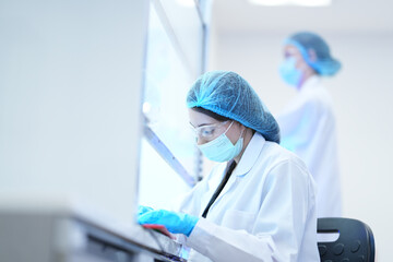 A medical researcher works in a sterile laminar flow hood to prevent contamination of her samples....