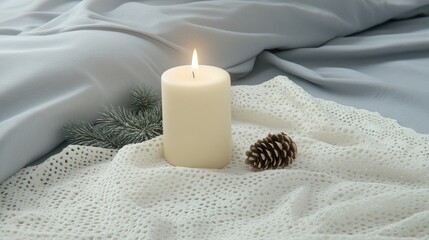 A single candle flickers in an antique brass holder, surrounded by pine cones and evergreen branches, as snow gently falls outside the window on a winter's day