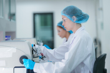 Female medical laboratory technologists in full protective gear work efficiently in a row,...