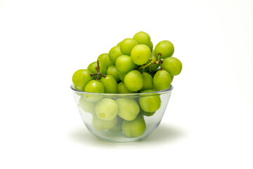 Close up of fresh green grapes with water drops on glass bowl isolated on white background