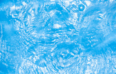 Blue water with ripples on the surface. Defocus blurred transparent blue colored clear calm water surface texture with splashes and bubbles. Water waves with shining pattern texture background.