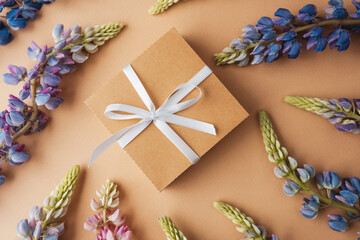Gift box and lupine flowers on beige background