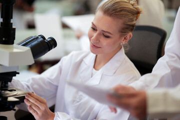 A biotech engineer uses an advanced digital microscope with AI powered image analysis to observe...