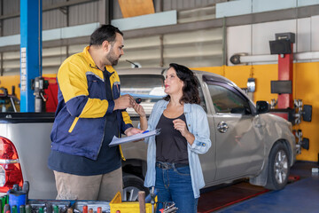 garage services concept,Indian auto mechanic man holding clipboard paper,explaining details of a car maintenance and repair to caucasian female then a woman owner giving a car key to repairman
