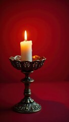 Ornate candle holder with lit candle on deep red backdrop, picture, burning