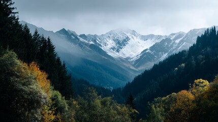 Fototapeta premium Majestic mountain landscape with snow peaks and lush green trees during cloudy weather